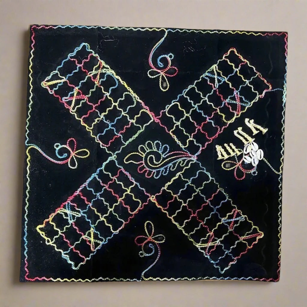 Black Barjees cloth board with colorful embroidered paths, playing pieces and shells.