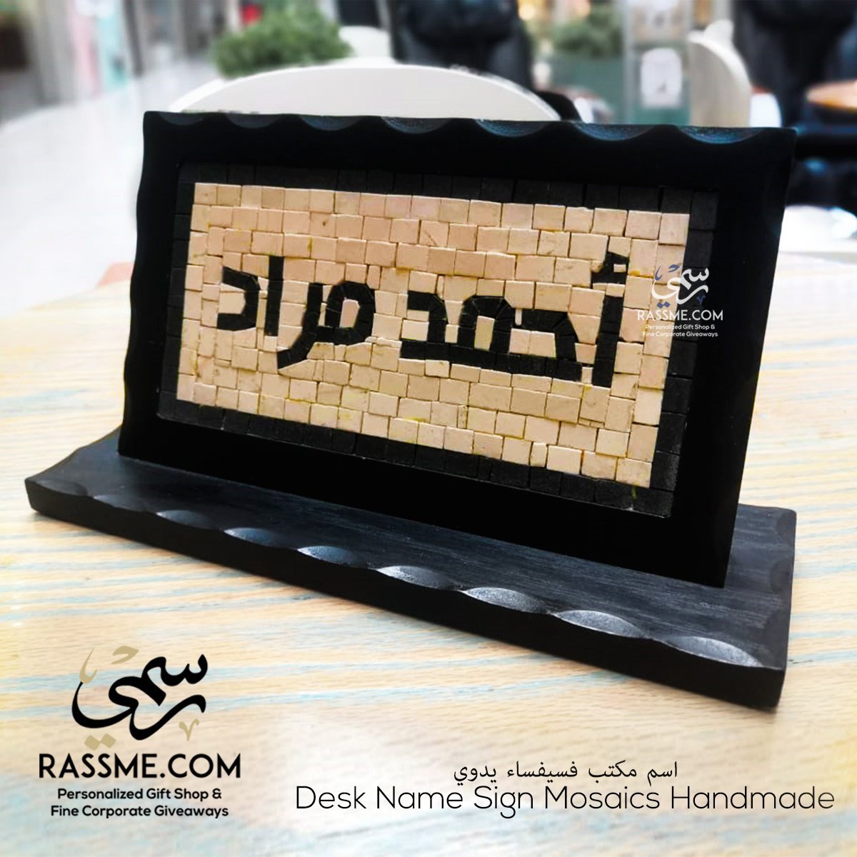 Wooden desk name sign with raised Arabic lettering on a stone mosaic background