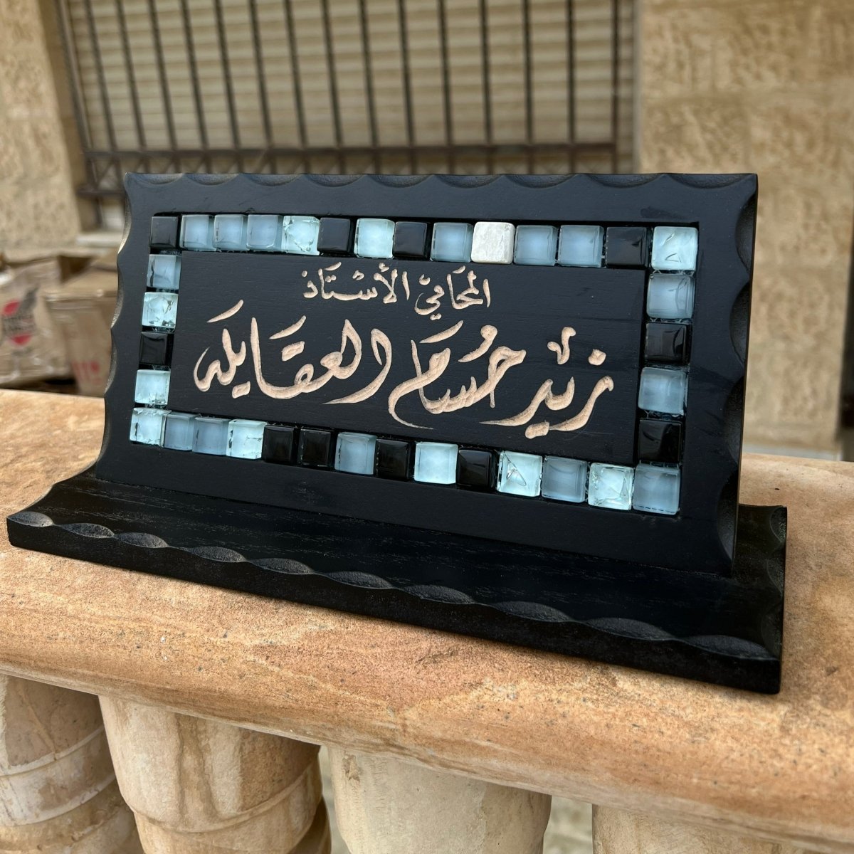 Black desk name sign with blue mosaic stones and Arabic calligraphy