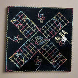 Black Barjees cloth board with colorful embroidered paths, playing pieces and shells.