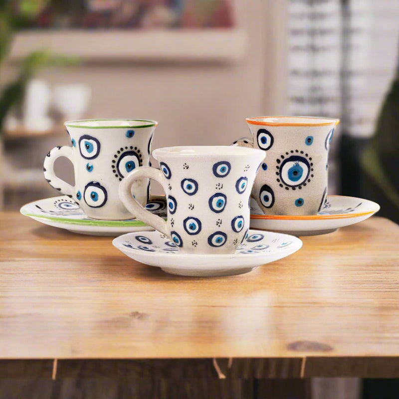 Ceramic coffee cups and saucers decorated with blue-eye motifs.