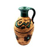 Handmade decorative oil vase with a green handle and Arabic lettering on a warm ochre body