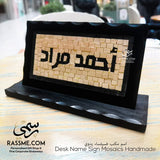 Wooden desk name sign with raised Arabic lettering on a stone mosaic background