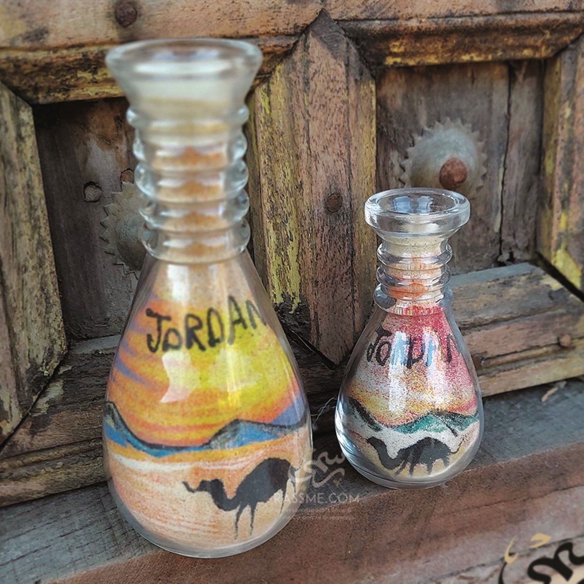 Two colored sand-art bottles depicting a desert scene with Jordan lettering.