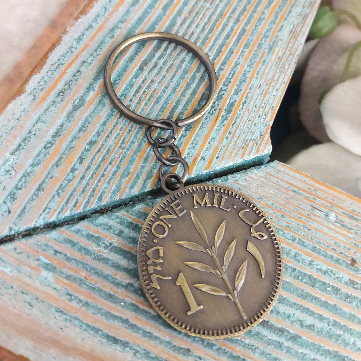 Palestine One Mil coin-design keychain resting on a wooden surface.