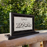 Rotating black wooden desk name sign with Arabic calligraphy on a white panel