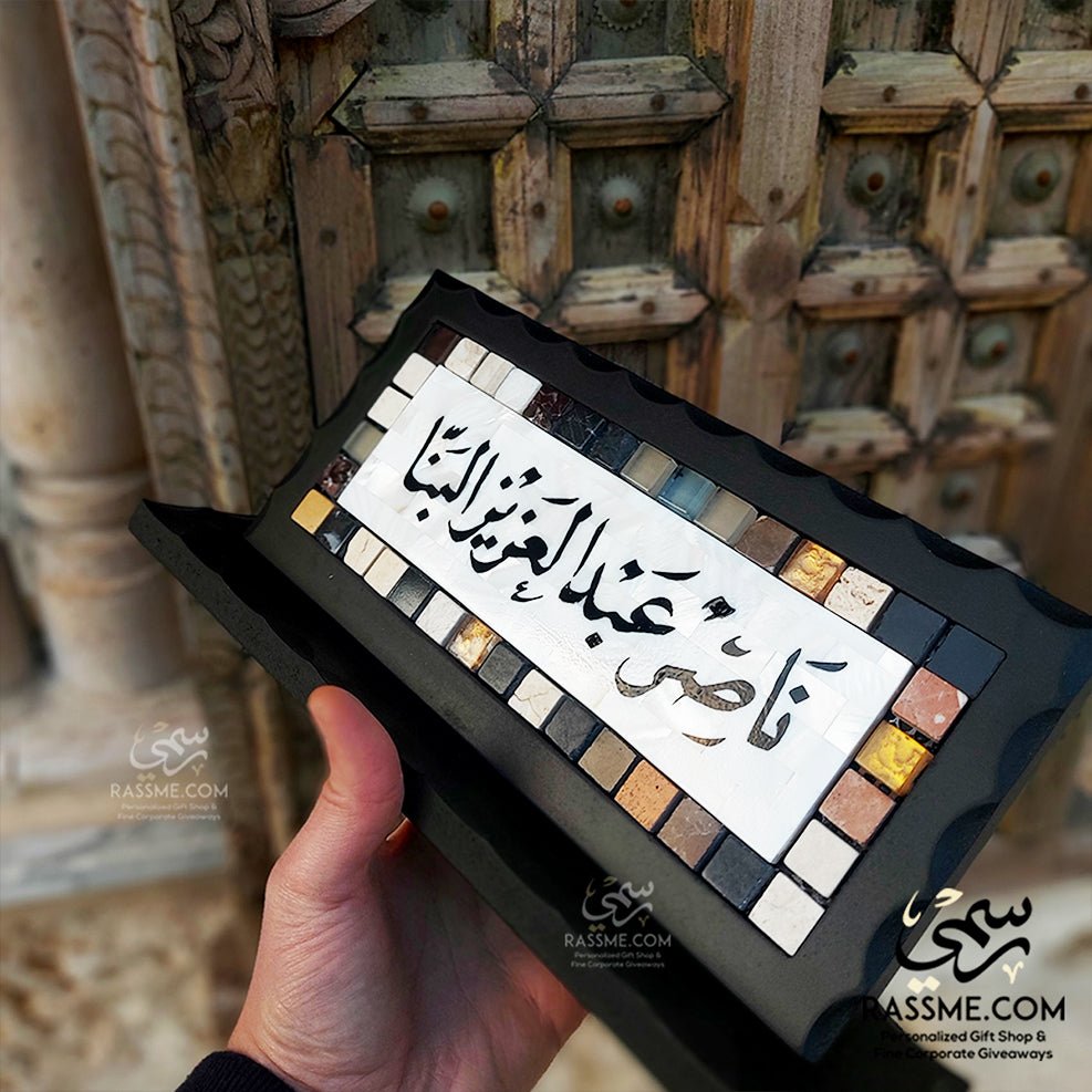 Mother-of-pearl desk name sign with black Arabic calligraphy and mosaic border